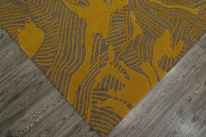 A close-up of a mustard yellow and gray patterned rug corner laid on a gray wood floor.