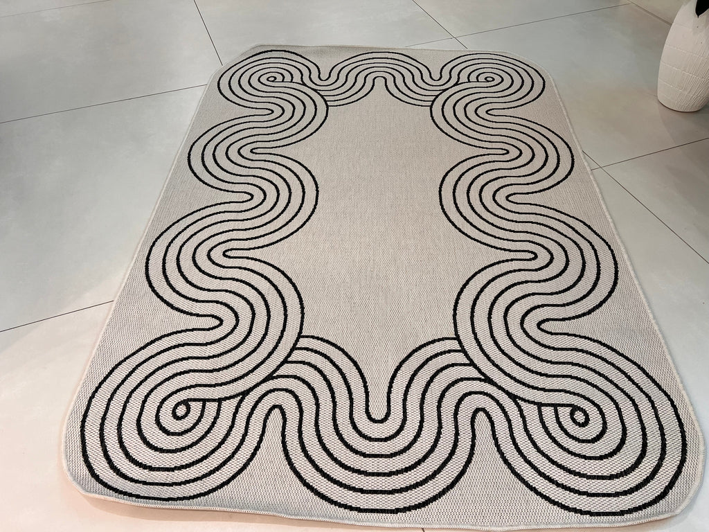 Indoor/Outdoor Ivory Rug with Black Geometric Swirl and Live Edge Design.