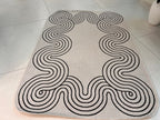 Indoor/Outdoor Ivory Rug with Black Geometric Swirl and Live Edge Design.