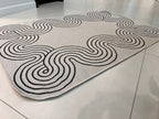 Indoor/Outdoor Ivory Rug with Black Geometric Swirl and Live Edge Design.