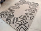 Indoor/Outdoor Ivory Rug with Black Geometric Swirl and Live Edge Design.