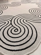 Indoor/Outdoor Ivory Rug with Black Geometric Swirl and Live Edge Design.