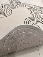 Indoor/Outdoor Ivory Rug with Black Geometric Swirl and Live Edge Design.