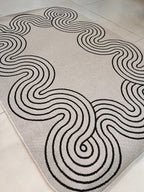 Indoor/Outdoor Ivory Rug with Black Geometric Swirl and Live Edge Design.