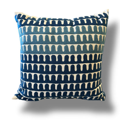 A square throw pillow with a navy blue and cream ikat-style horizontal pattern, shown against a plain white background with a soft drop shadow.