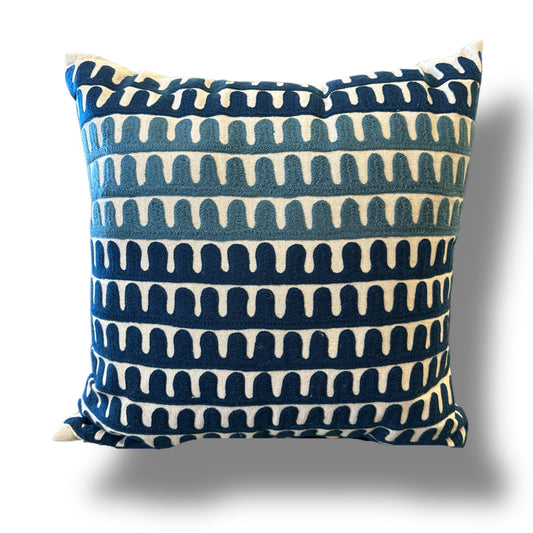 A square throw pillow with a navy blue and cream ikat-style horizontal pattern, shown against a plain white background with a soft drop shadow.