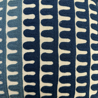 A close-up of a textured fabric with a repeating vertical wavy pattern in navy blue and cream.