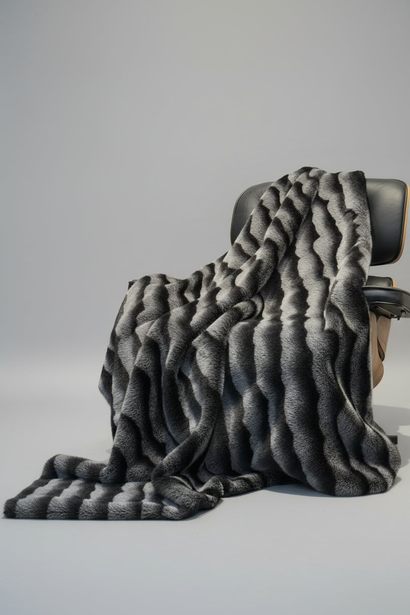 Gray textured throw blanket draped over a chair on a light gray background