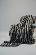 Gray textured throw blanket draped over a chair on a light gray background