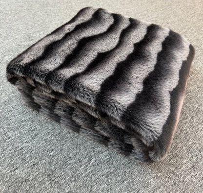 Folded fur blanket with a striped pattern on a textured surface
