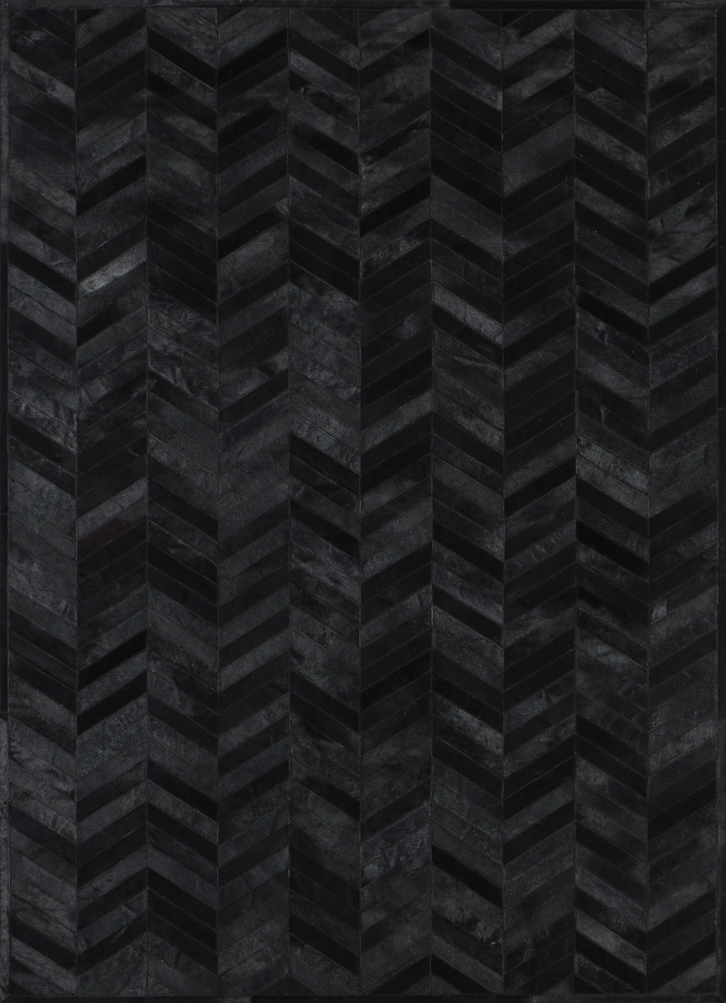 A close-up view of a black patchwork cowhide rug with a geometric pattern.