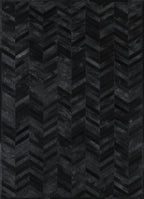 A close-up view of a black patchwork cowhide rug with a geometric pattern.