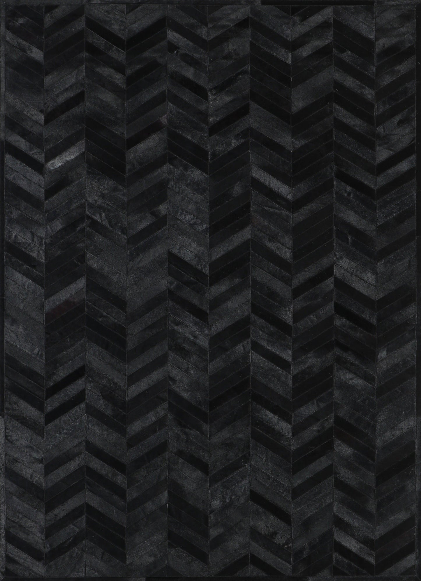 A close-up view of a black patchwork cowhide rug with a geometric pattern.