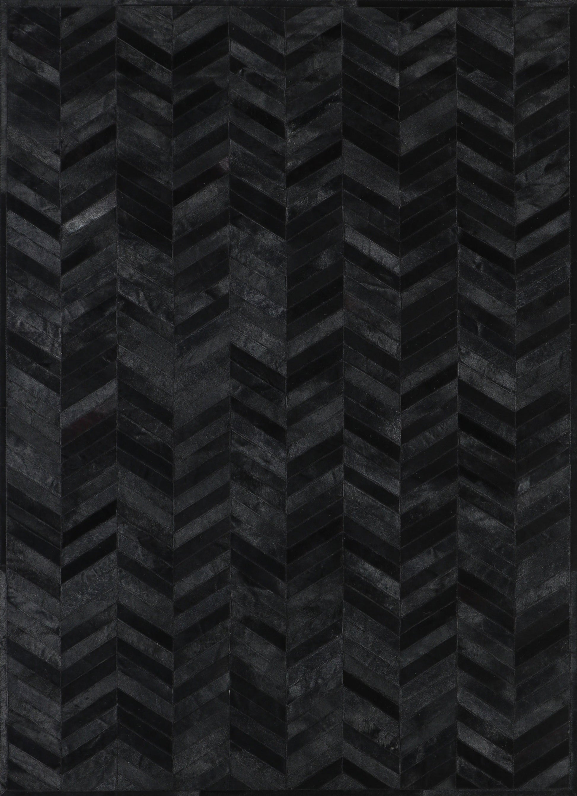 A close-up view of a black patchwork cowhide rug with a geometric pattern.