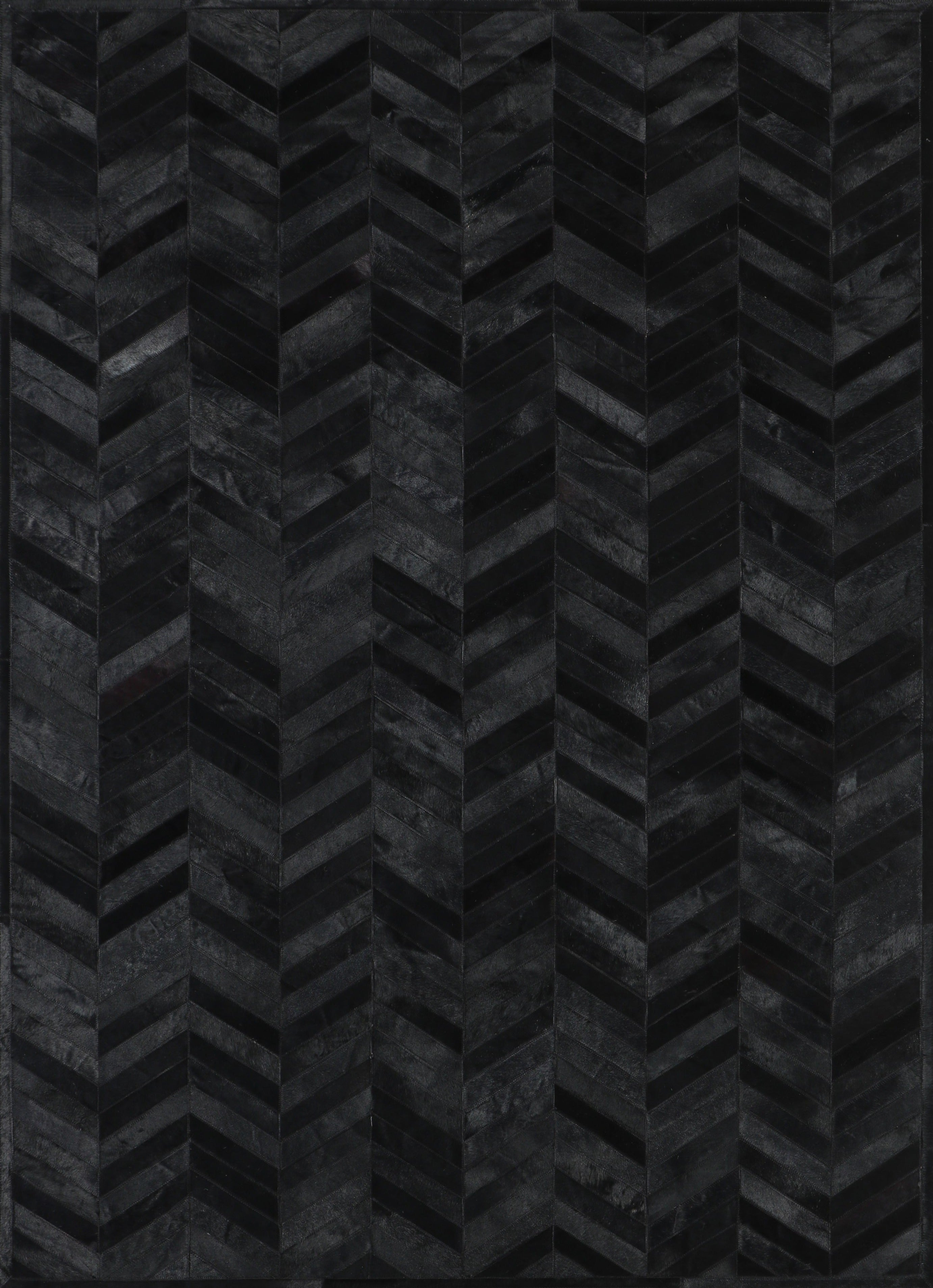 A close-up view of a black patchwork cowhide rug with a geometric pattern.