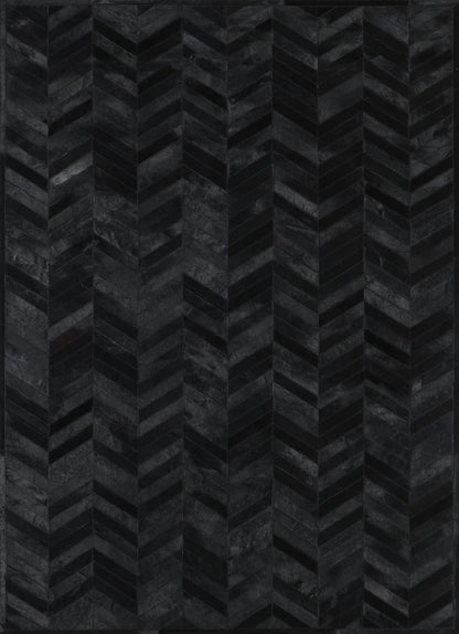 A close-up view of a black patchwork cowhide rug with a geometric pattern.