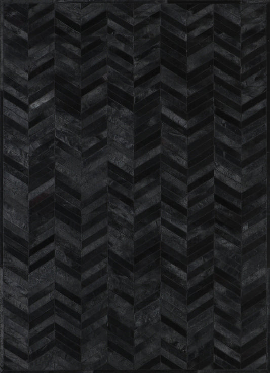 A close-up view of a black patchwork cowhide rug with a geometric pattern.